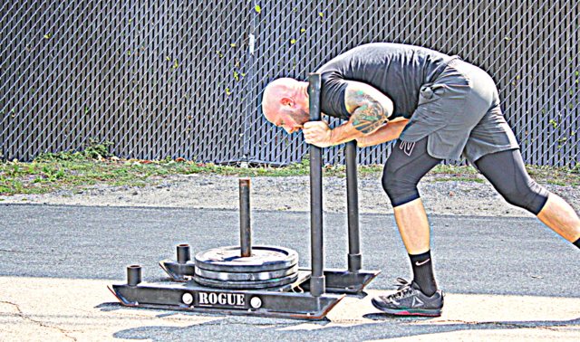 Coach Chad Kucera pushing sleds